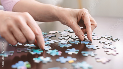 Elderly woman hands doing jigsaw puzzle closeup photo