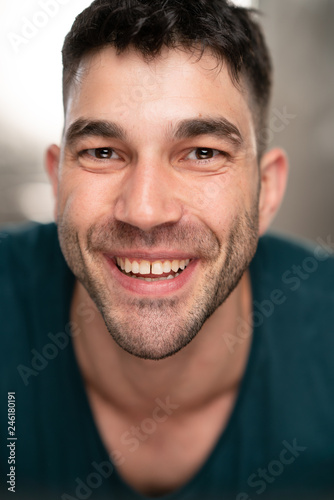 Handsome caucasian white male with black short hair and stubble with blue t shirt smiling