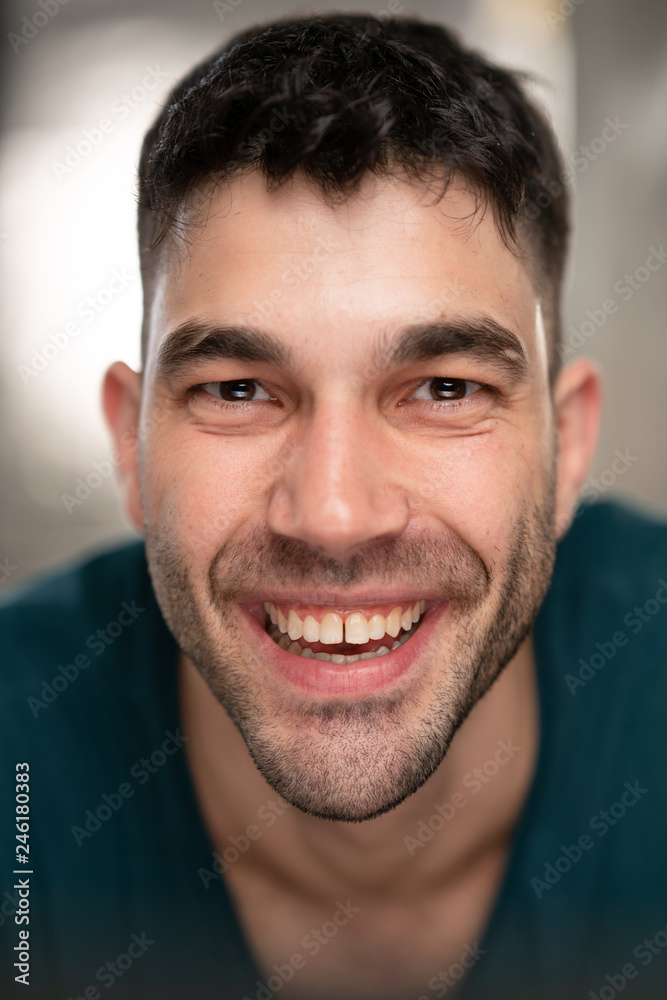 Handsome caucasian white male with black short hair and stubble with blue t shirt smiling Handsome caucasian white male with black short hair and stubble with blue t shirt smiling