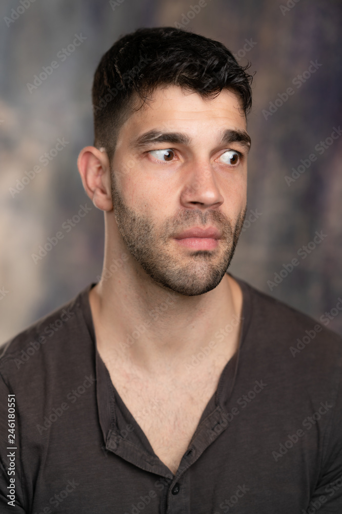 Handsome caucasian white male with black short hair and stubble with brown t shirt, looking worried Handsome caucasian white male with black short hair and stubble with brown t shirt, looking worried