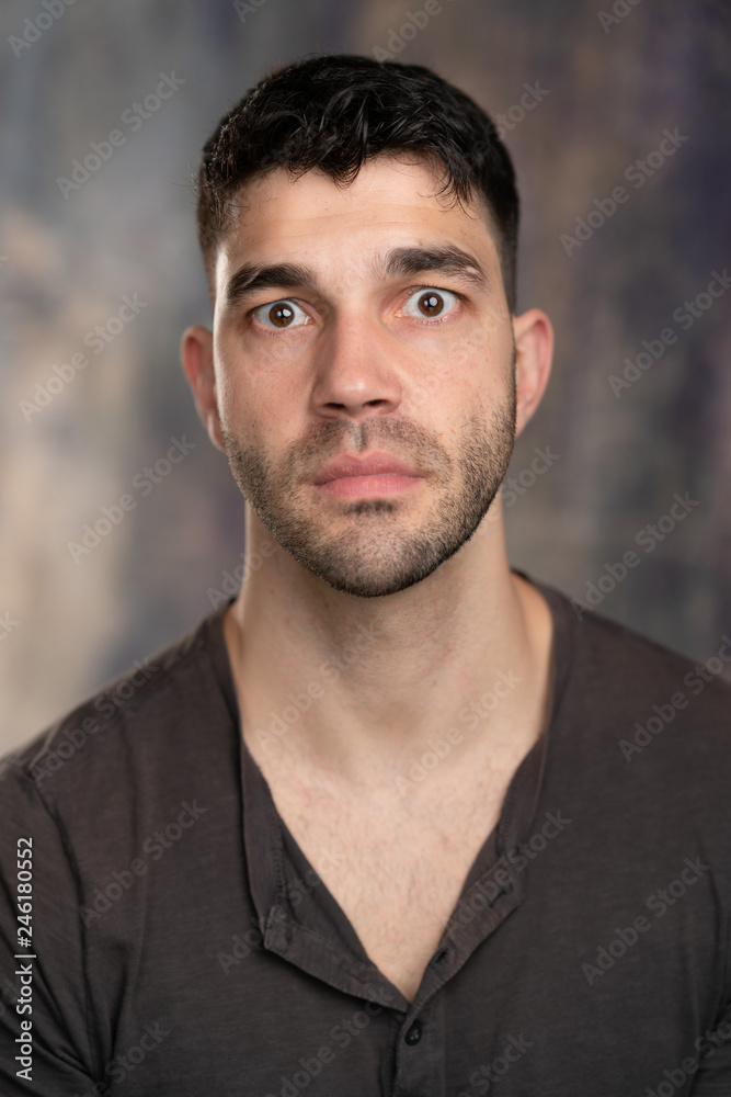 Handsome caucasian white male with black short hair and stubble with brown  t shirt, looking surprised Stock Photo | Adobe Stock