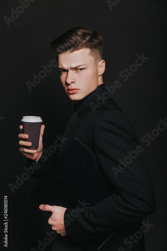Young handsome businessman in classic black jacket and white shirt. It is time for coffee break! Handsome young man holding coffee cup