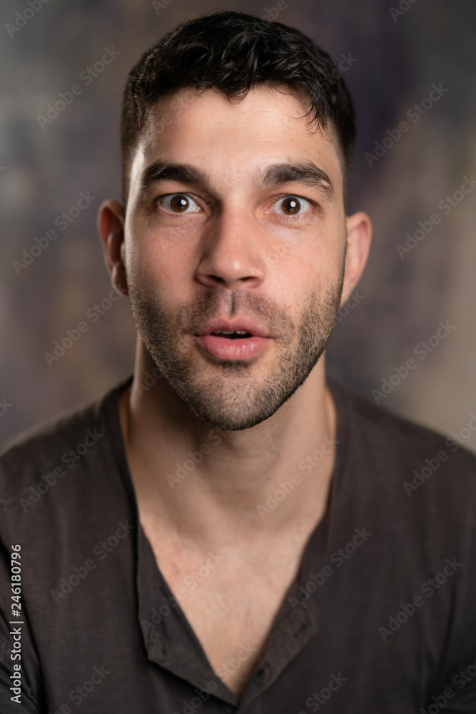 Handsome caucasian white male with black short hair and stubble with brown t shirt, looking impressed Handsome caucasian white male with black short hair and stubble with brown t shirt, looking impressed