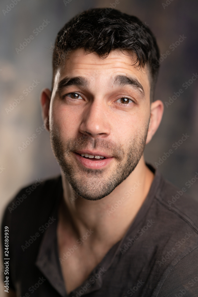 Handsome caucasian white male with black short hair and stubble with brown t shirt, looking smug Handsome caucasian white male with black short hair and stubble with brown t shirt, looking smug