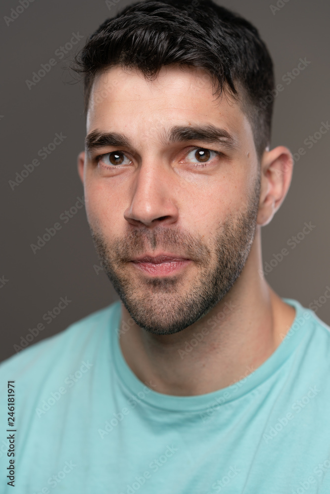 Handsome caucasian white male with black short hair and stubble with light blue t shirt Handsome caucasian white male with black short hair and stubble with light blue t shirt
