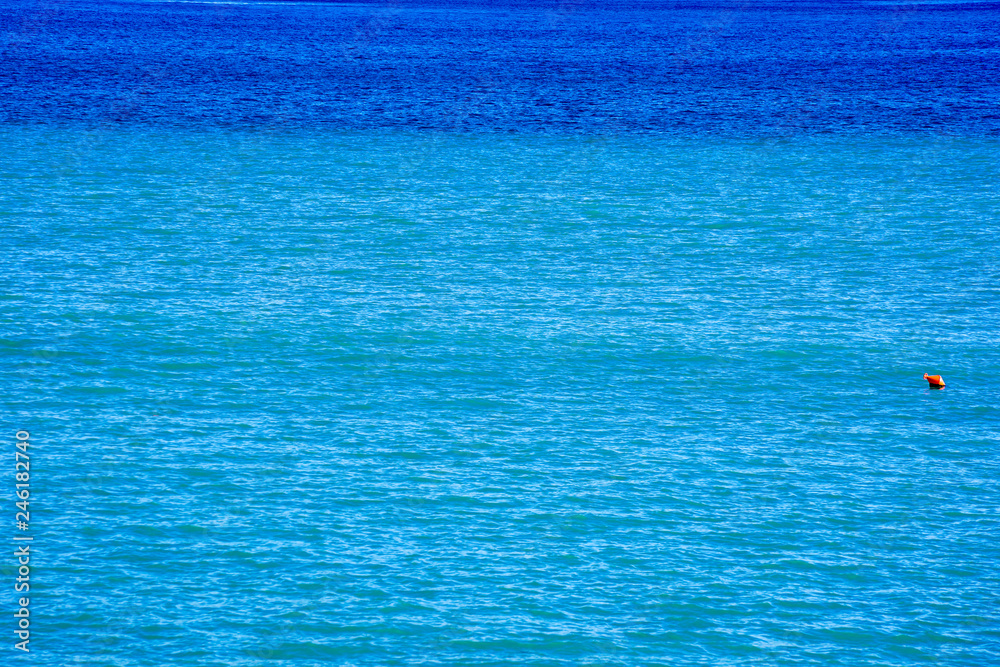 blue and turquoise sea, a red buoy on the right side