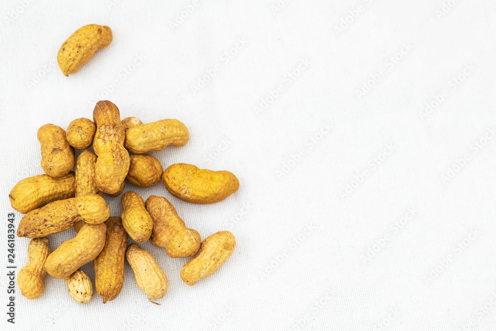 Peanuts in the peel in a pile on linen fabric. Minimalism. Place for text Peanuts in the peel in a pile on linen fabric. Minimalism. Place for text