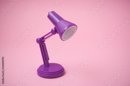 Closeup of mini purple modern lamp of desk on pink background