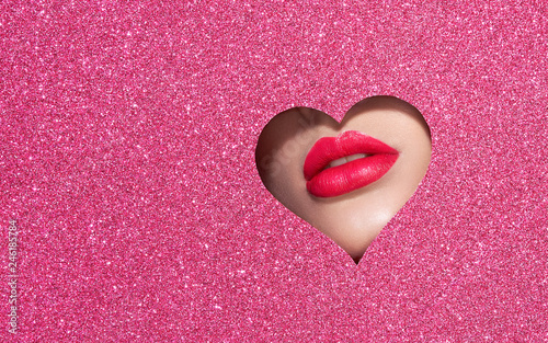 Beautiful Plump Bright Lips Of a Young Beautiful Woman with Red Lipstick Look Into the Pattern of Heart Shaped made of Colored Paper. Holiday Patterns. Valentine's Day. Beautiful Love Make-up