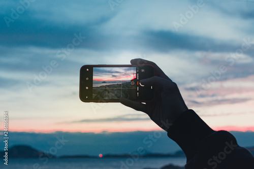 hand holding smart phone with landscape background with copy space