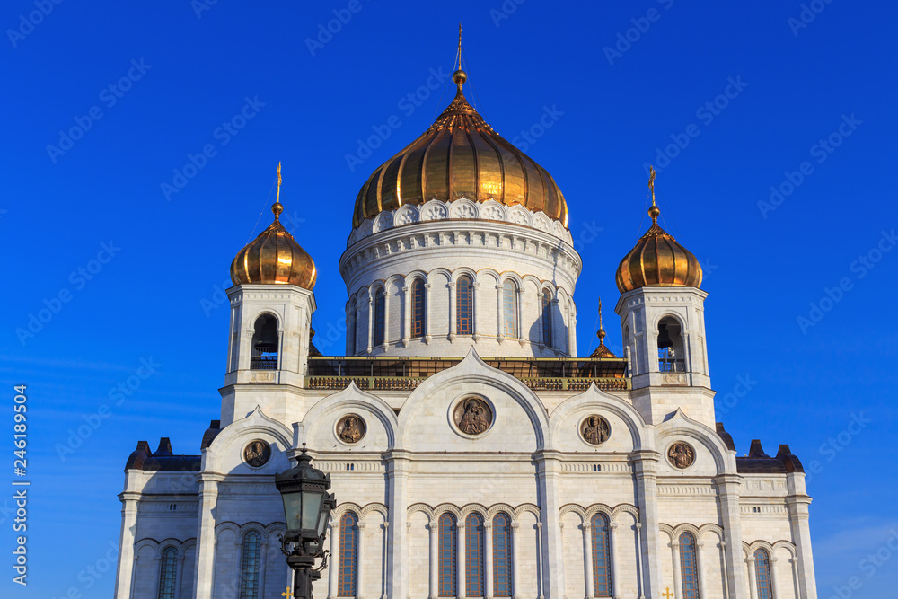 Walls and golden domes of Cathedral of Christ the Saviour against blue sky in sunny spring morning