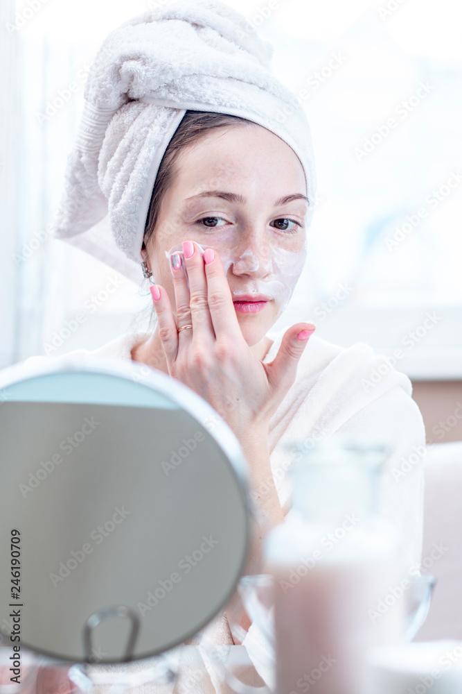 Beautiful happy woman applying cream on face moisturizing the skin. Hygiene and care for the skin at home Beautiful happy woman applying cream on face moisturizing the skin. Hygiene and care for the skin at home
