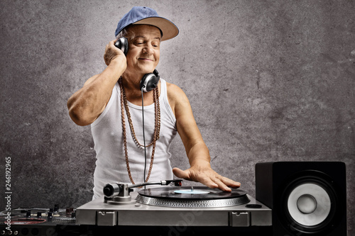 Mature dj with headphones playing music at a turntable