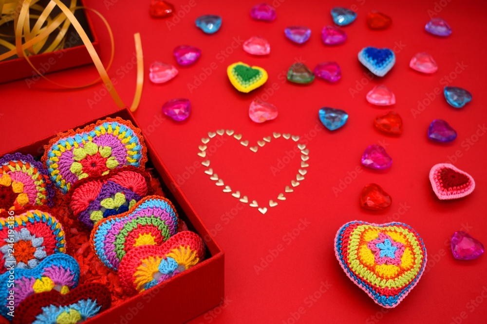Fototapeta premium Knitted hearts in a gift box on a red background. Valentine's Day, love, handmade, amigurumi, hobby, decoration, greeting card, creative.