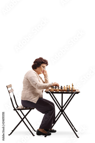 senior woman with a chessboard at a table looking at the chess figure and thinking