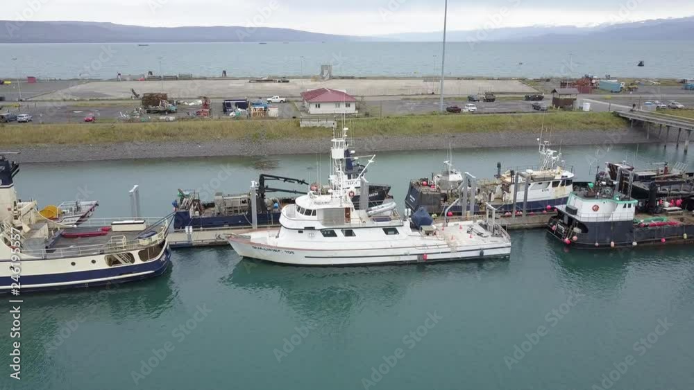 Aerial shot flying over large commercial fishing boats docked in the harbor of Homer, Alaska USA