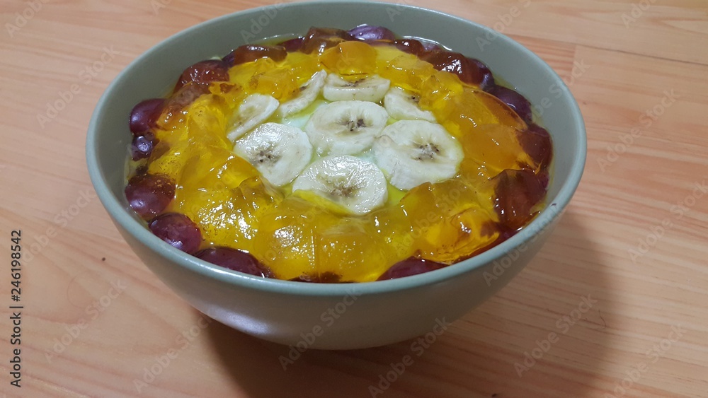Creamy tasty sweet custard with banana pieces on surface inbowl on wooden floor Creamy tasty sweet custard with banana pieces on surface inbowl on wooden floor