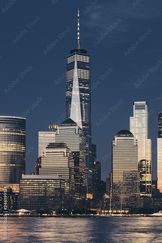 New York City business district skyline at dusk, color toning applied, USA.