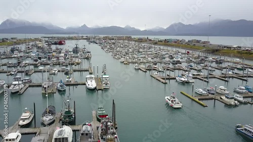Aerial shot flying over the busy boat harbor in the beautiful small city of Homer, Alaska, with a magnificent backdrop in the distance