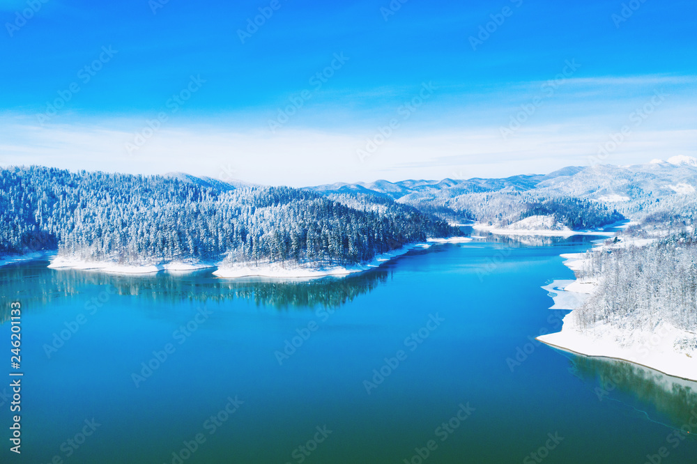 Croatian nature landscape, beautiful winter panorama of Lokvarsko lake and woods under snow in Gorski kotar and Risnjak mountain in background from drone 