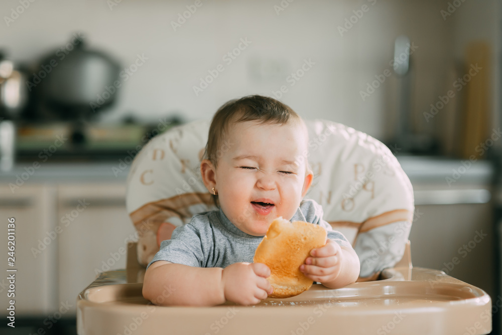 baby in the kitchen in the high chair there is a piece of bread baby in the kitchen in the high chair there is a piece of bread