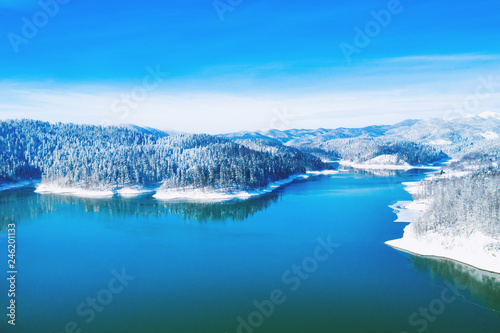 Croatian nature landscape, beautiful winter panorama of Lokvarsko lake and woods under snow in Gorski kotar and Risnjak mountain in background from drone 