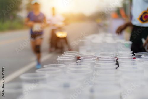 Runner take a water in a marathon race with sunrise