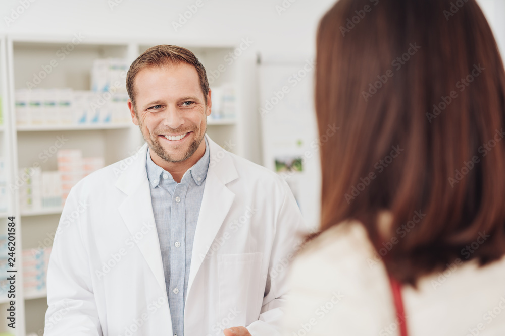 Fototapeta premium Male pharmacist smiling as he attends to a woman
