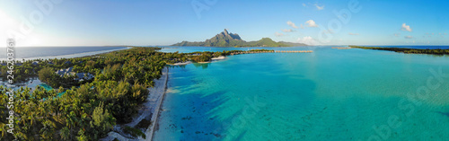 Aerial panoramic landscape view of the island of Bora Bora in French Polynesia with the Mont Otemanu mountain surrounded by a turquoise lagoon, motu atolls, re