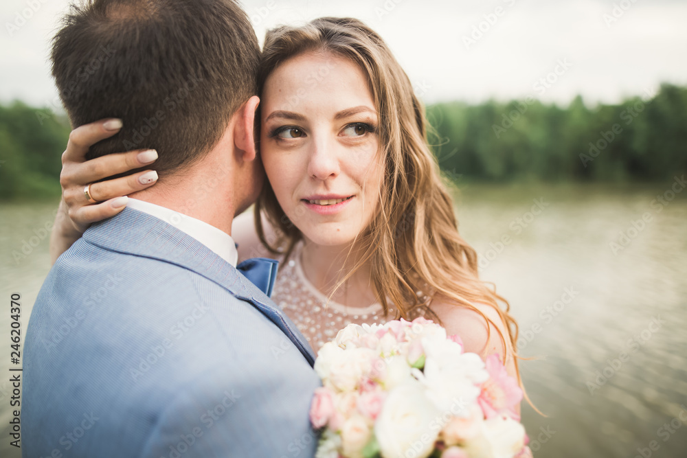 Bride and groom holding beautiful wedding bouquet. Lake, forest