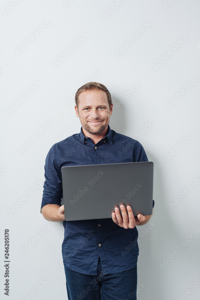 Man with laptop standing against white wall Man with laptop standing against white wall