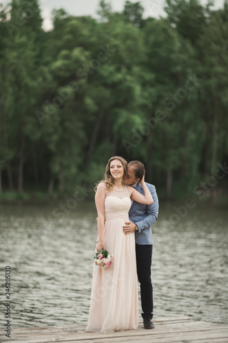 Elegant beautiful wedding couple posing near a lake at sunset © olegparylyak