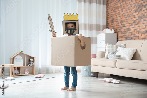 Cute little boy playing cardboard armor in living room photo