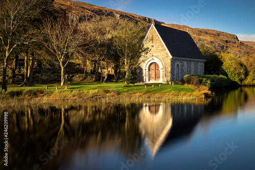 Autumnal mirror reflections of St. Finnbarr's oratory on Gougane Barra lake in West Cork.