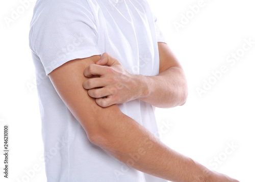 Young man scratching arm on white background, closeup. Annoying itch
