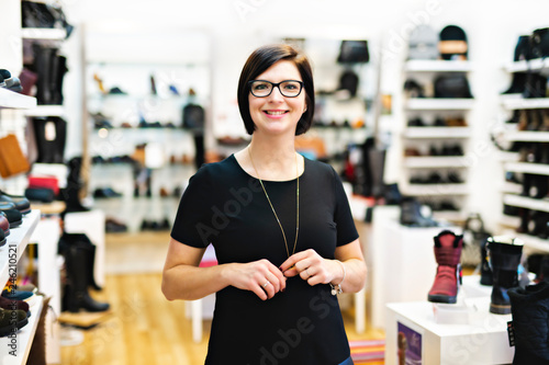 A sale, shopping and people concept happy young woman or shop assistant at store photo