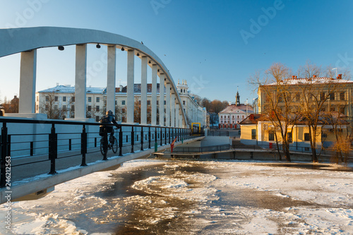 Pedestrian bridge Kaarsild, Emajõgi river and the view on the Town Hall during winter in Tartu, Estonia. Man is riding the bicycle