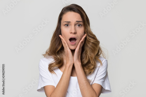 Shocked woman feeling terrified looking at camera on white studio wall  stressed horrified frightened lady in panic with scared face screaming having phobia posing on light blank background  portrait