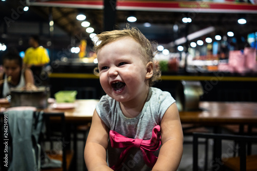 Baby smiling and looking up to camera. baby girl laughing in a night cafe you devilish laugh