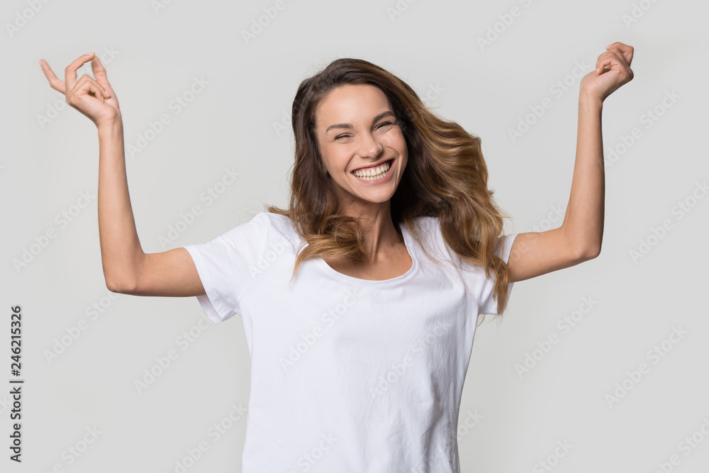 Happy cheerful young woman jumping feeling joy isolated on white studio wall blank background, excited ecstatic girl laughing rejoicing dancing enjoying freedom looking at camera, portrait