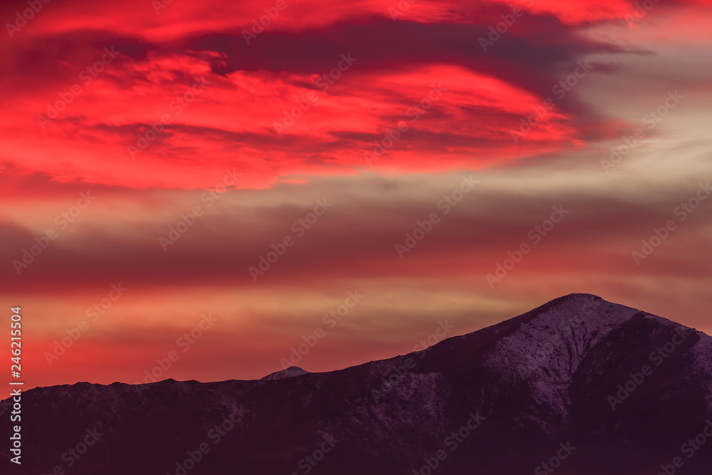 a spectacular red cloud above the mountains /a landscape at sunset with mountains  drawn in the sky