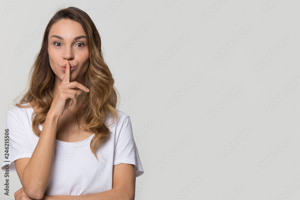 Young woman holding finger on lips mouth to keep it quiet hush standing isolated on white grey blank studio background with copy space, millennial gossip girl showing shh gesture secret in silence Young woman holding finger on lips mouth to keep it quiet hush standing isolated on white grey blank studio background with copy space, millennial gossip girl showing shh gesture secret in silence