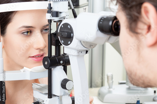 High technology concept health for eyes care - The optician ophthalmology doctor optometrist in the eyes clinic using a binocular slit-lamp to a young woman for an eye control