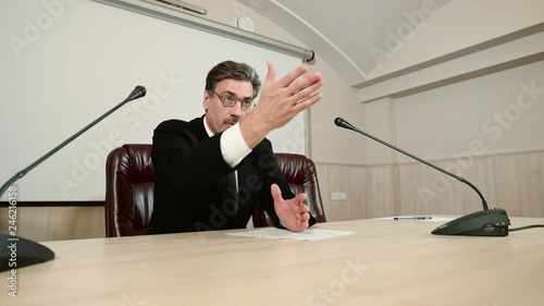 Politician severely answers a question at a press conference, gesturing by hands and emotionally speaking. Election agitation.