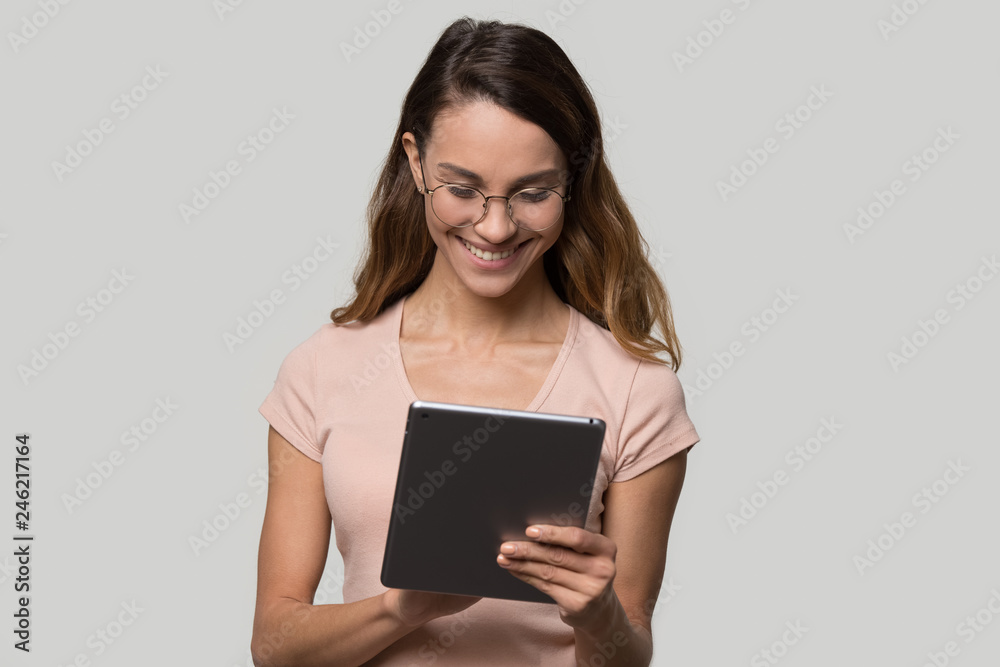 Happy teen girl using digital tablet surfing online content chatting in social media, smiling young woman user shopper consumer holding pc doing shopping online isolated on blank studio background Happy teen girl using digital tablet surfing online content chatting in social media, smiling young woman user shopper consumer holding pc doing shopping online isolated on blank studio background