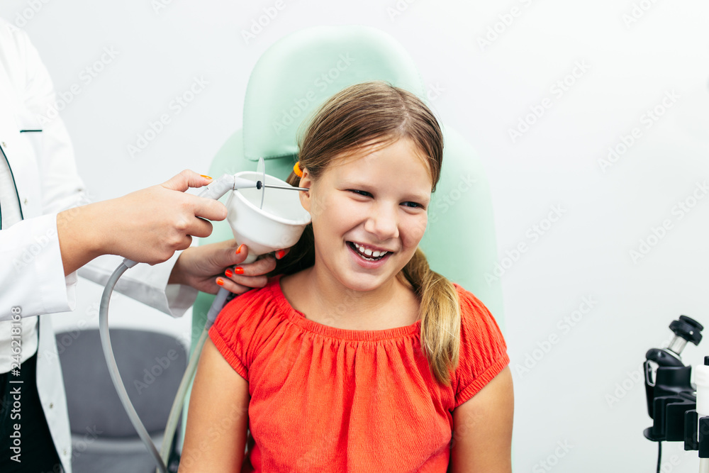 Young girl at medical examination or checkup in otolaryngologist's office. Ear irrigation and earwax removal. Young girl at medical examination or checkup in otolaryngologist's office. Ear irrigation and earwax removal.