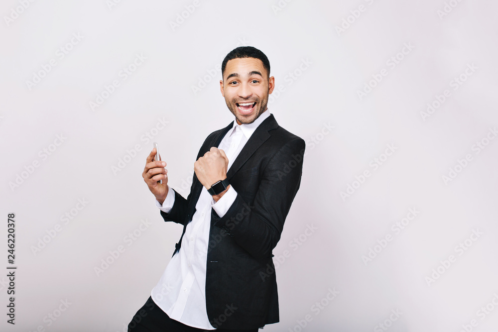 Portrait young handsome man in white shirt, black jacket having fun, smiling to camera on white background. Success, expressing true positive emotions, good results, happiness, smiling