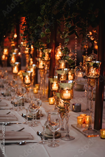 Hindu wedding reception dinner. Tables served with greenery, shiny candles and rose gold decor stands in the restaurant © IVASHstudio