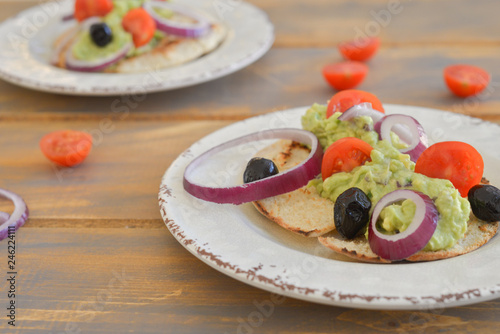 Healthy breakfast. Avocado salad with sherry tomatoes olives and onion on pita bread. On wooden table. flat lay top view copy space 