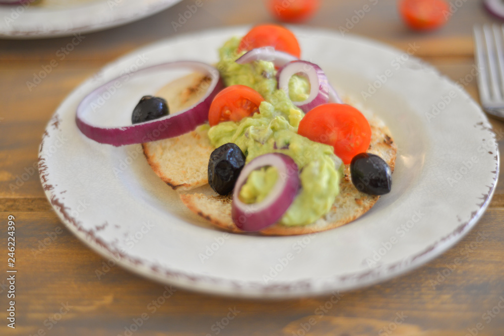 Healthy breakfast. Avocado salad with sherry tomatoes olives and onion on pita bread. On wooden table. flat lay top view copy space Healthy breakfast. Avocado salad with sherry tomatoes olives and onion on pita bread. On wooden table. flat lay top view copy space